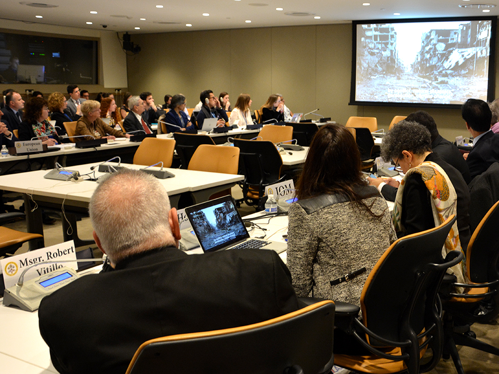 Participants watch Pope Francis' message on migrants and refugees