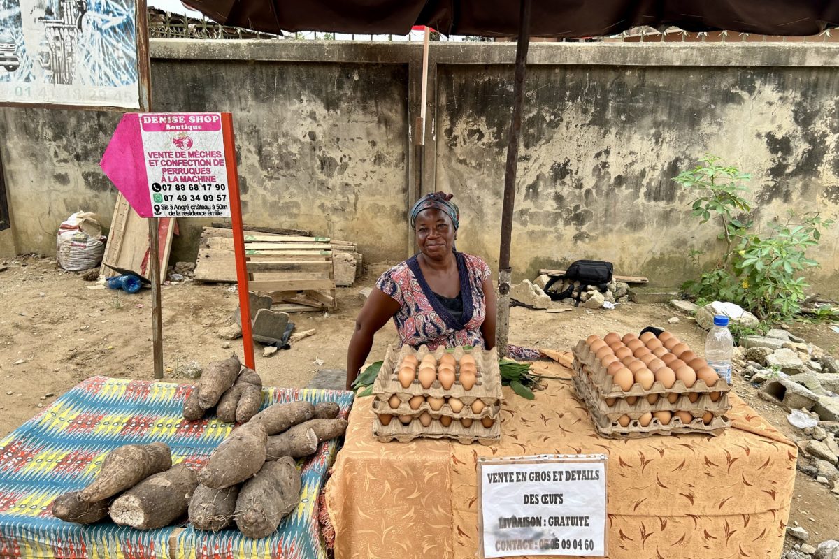 A returned migrant sells produce from her market booth in Ivory Coast