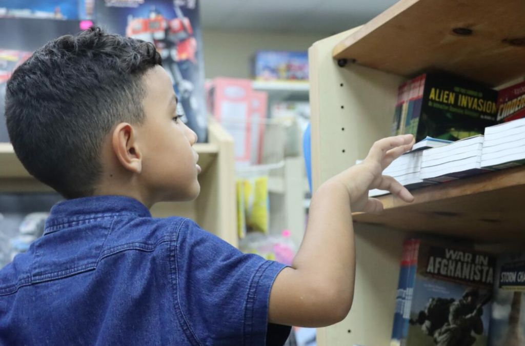 A Venezuelan refugee in Trinidad child chooses a story book.