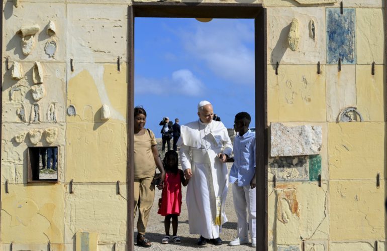 Pope Leo XIV and a migrant family at the 'Gateway to Europe' sculpture on the Italian island of Lampedusa, dedicated to migrants lost at sea while attempting to reach Europe. Taken during the Apostolic Visit to Lampedusa on 4 July 2026.